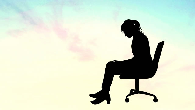オフィスチェアに座ってうつむく女性